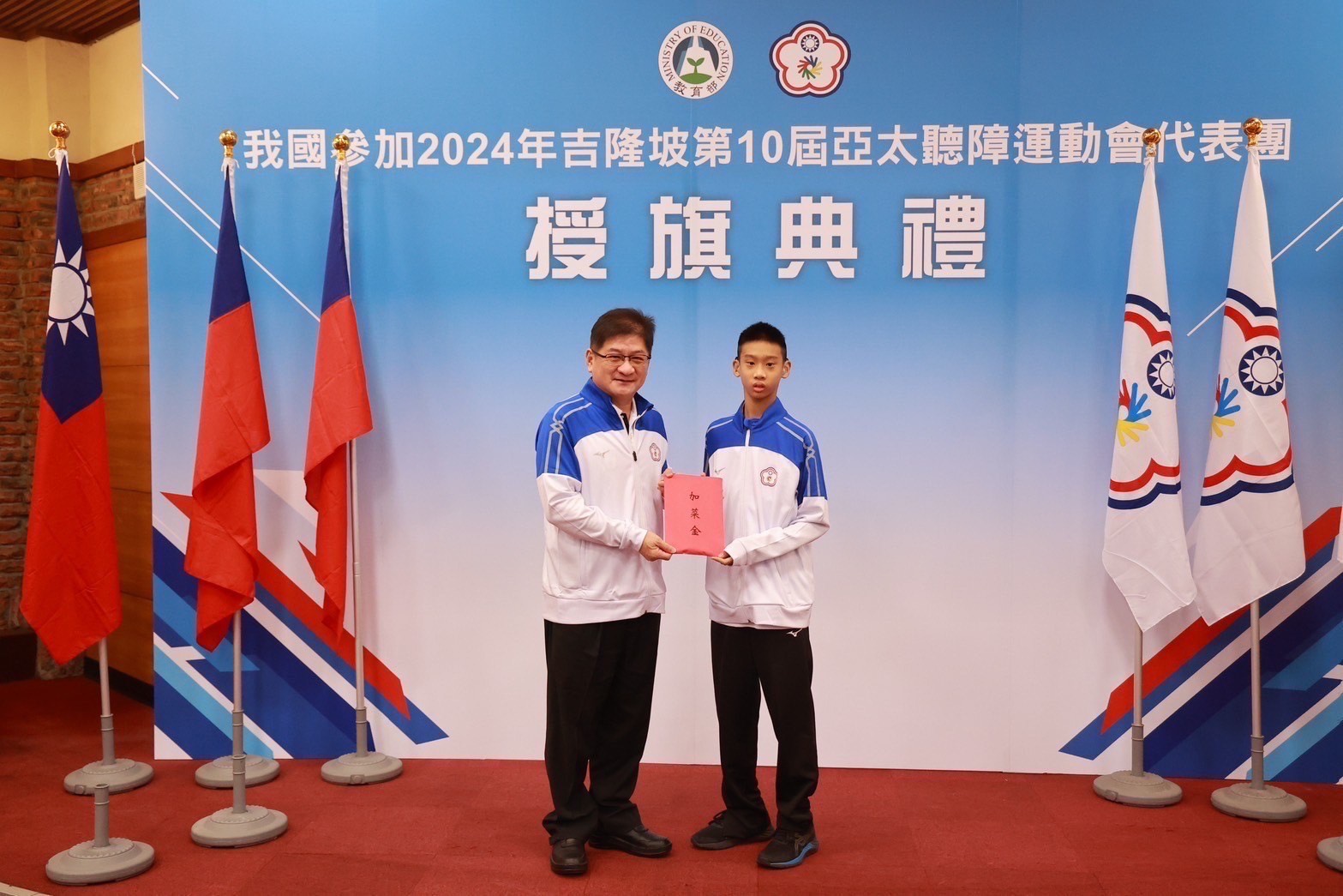 (圖)Deputy Director-general of the Sports Administration Hung Chih-chang (left) presented extra bonus, which was accepted by Chuang Cheng-ye (right), the youngest table tennis player in Taiwan’s 
