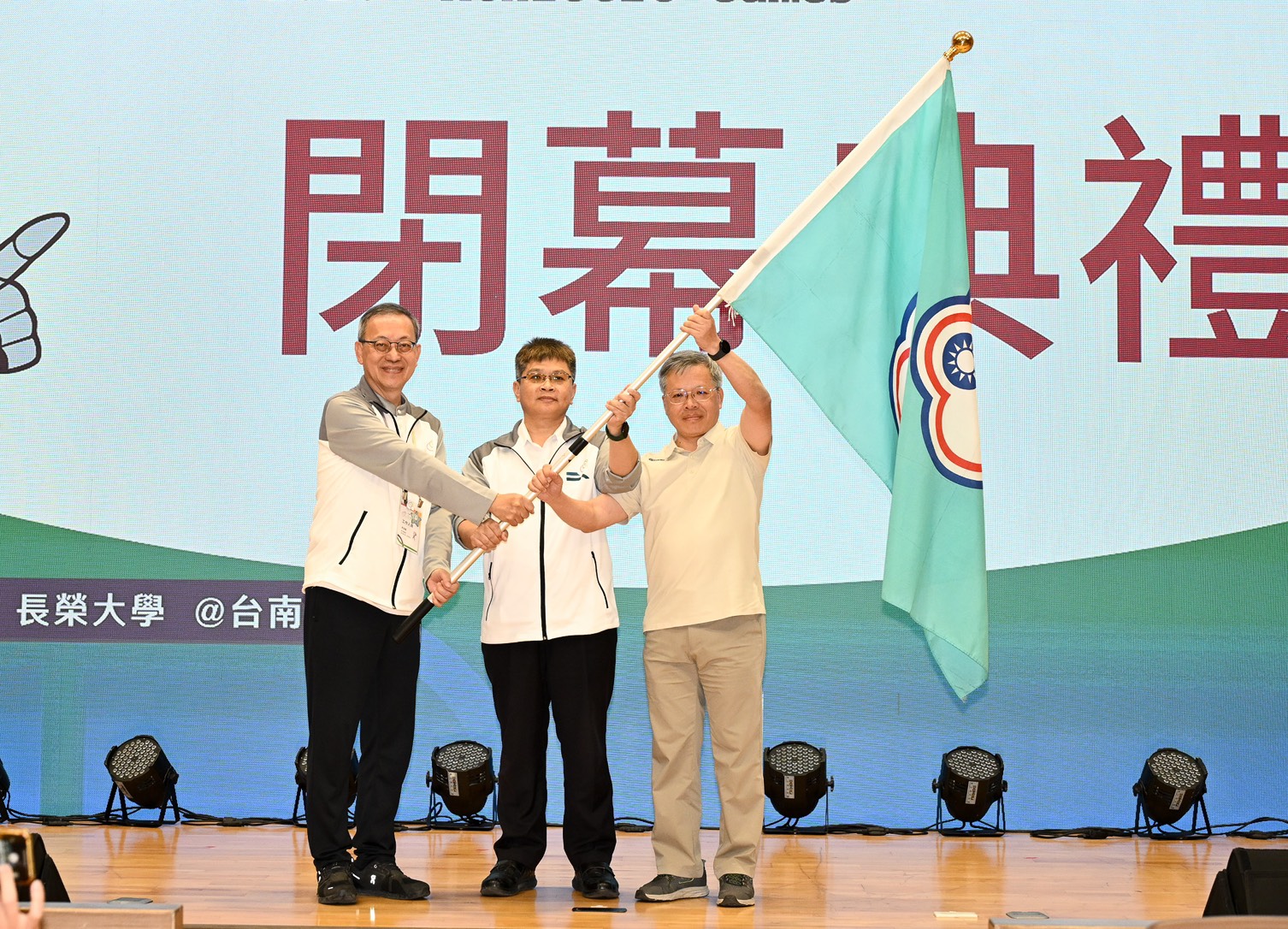 (圖)SA Deputy Director-General Fang Jui-wen (center) announced the closing of the 2025 National Intercollegiate Athletic Games (NIAG). President Lee Yung-Lung of Chang Jung Christian University (left) handed over the games flag to President Hsiau Shu-San of National Central University (right), the host of the 2026 Games.